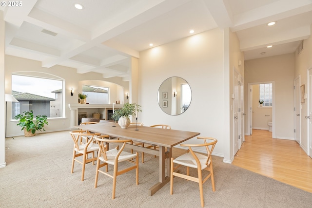 carpeted dining area featuring coffered ceiling and beam ceiling