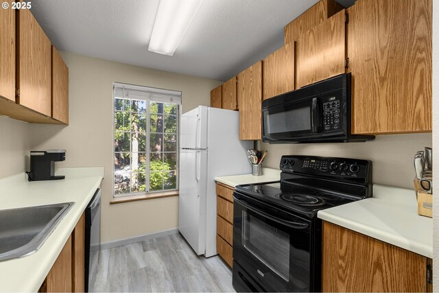 6160 SW Alice Ln Unit 203B, Beaverton, OR 97008 - kitchen featuring black appliances, light wood-style flooring, light countertops, and brown cabinetry