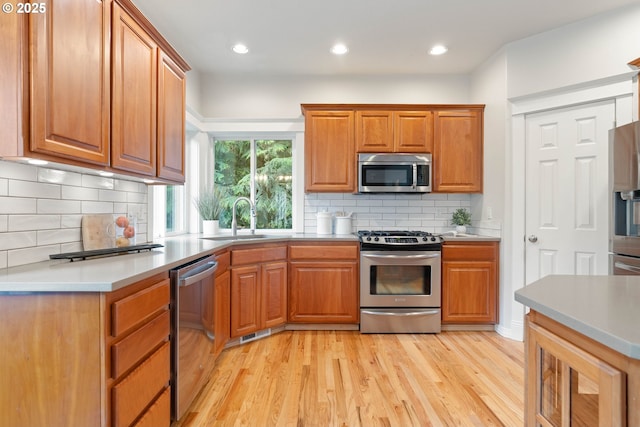 10540 SW Lancaster Rd, Portland, OR 97219 - kitchen featuring stainless steel appliances, a sink, light wood finished floors, brown cabinets, and recessed lighting