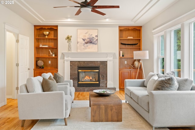 10540 SW Lancaster Rd, Portland, OR 97219 - living area with a ceiling fan, built in features, light wood-style floors, a high end fireplace, and a tray ceiling