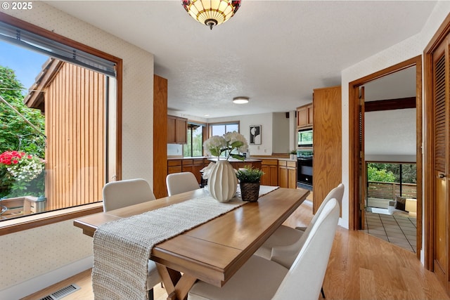 10315 SW 28th Ave, Portland, OR 97219 - dining space with wallpapered walls, light wood-style flooring, plenty of natural light, and a textured ceiling