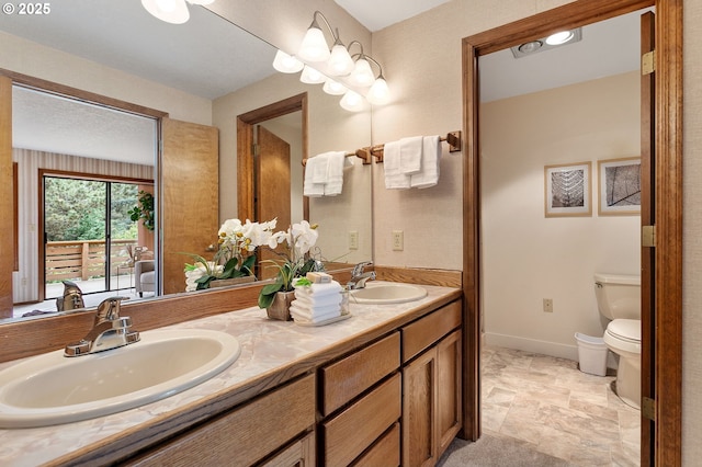 10315 SW 28th Ave, Portland, OR 97219 - bathroom featuring double vanity, toilet, baseboards, and stone finish flooring