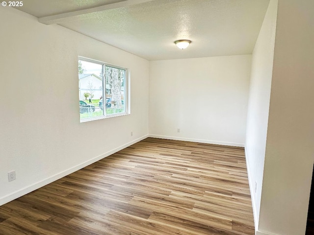 spare room featuring baseboards, a textured ceiling, and wood finished floors