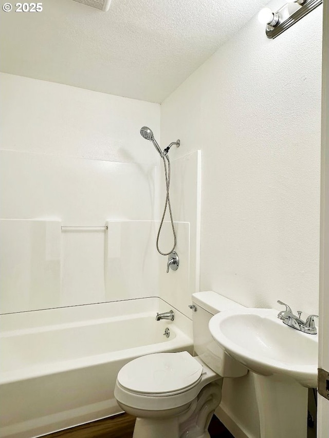 full bath with toilet, wood finished floors, shower / bathtub combination, and a textured ceiling