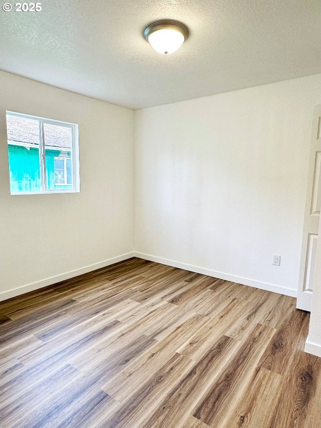 unfurnished room featuring wood finished floors, baseboards, and a textured ceiling