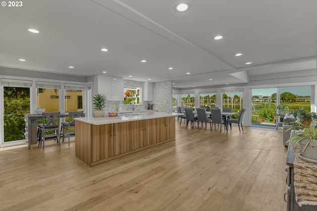 kitchen featuring a healthy amount of sunlight, a large island, light hardwood / wood-style flooring, and white cabinets