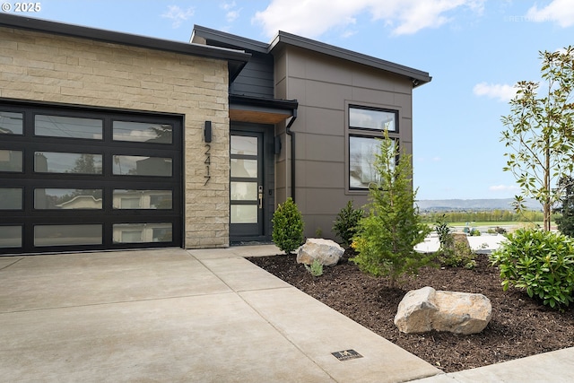 2417 E 6th St, Vancouver, WA 98661 - property entrance featuring concrete driveway, stone siding, and a garage