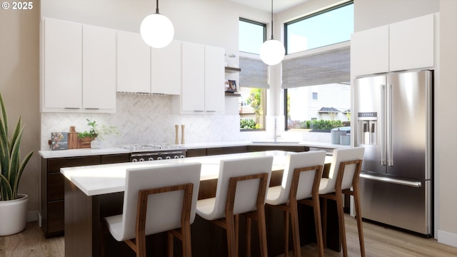 kitchen with a breakfast bar, a sink, high end fridge, open shelves, and tasteful backsplash