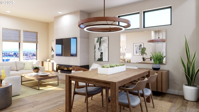 dining area featuring light wood-type flooring, a glass covered fireplace, baseboards, and recessed lighting