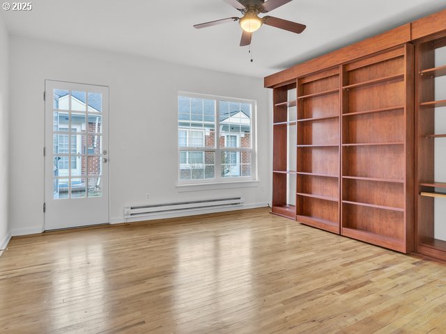 unfurnished living room with ceiling fan, hardwood / wood-style flooring, and a baseboard radiator