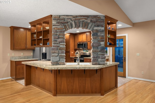 kitchen featuring open shelves, light wood-style floors, ornate columns, a sink, and appliances with stainless steel finishes