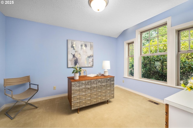 sitting room with a textured ceiling, baseboards, visible vents, and light carpet