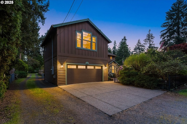 view of front facade with a garage, board and batten siding, fence, and concrete driveway