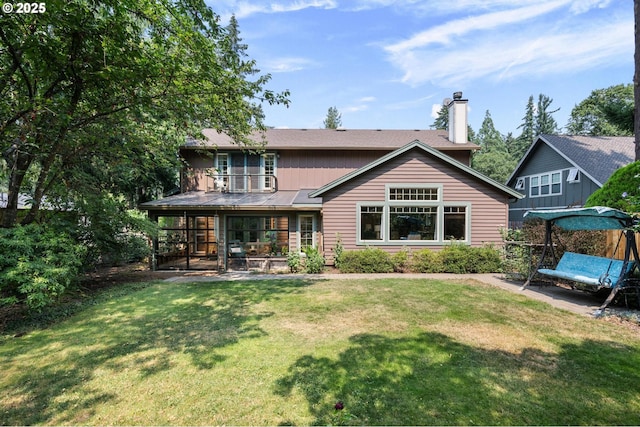 back of house with a sunroom, a chimney, and a yard