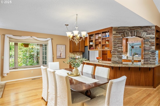 dining room with a textured ceiling, visible vents, baseboards, an inviting chandelier, and light wood-style flooring