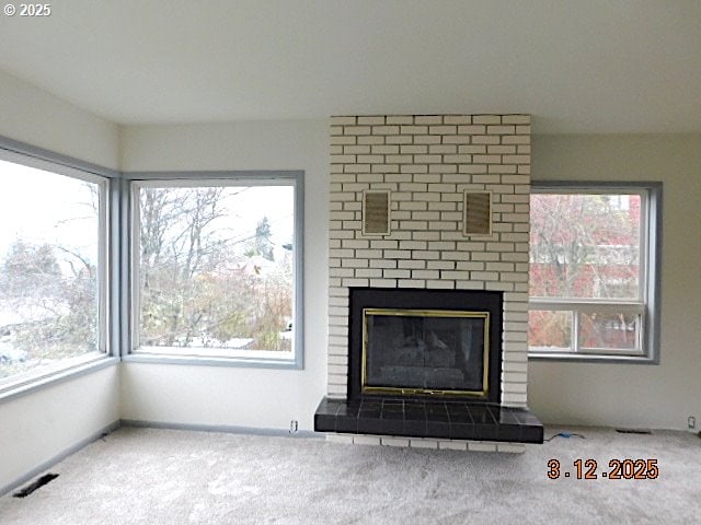 unfurnished living room with carpet floors, plenty of natural light, and a fireplace