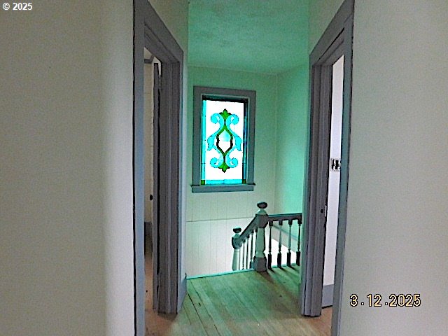 hall with an upstairs landing and light wood-style floors