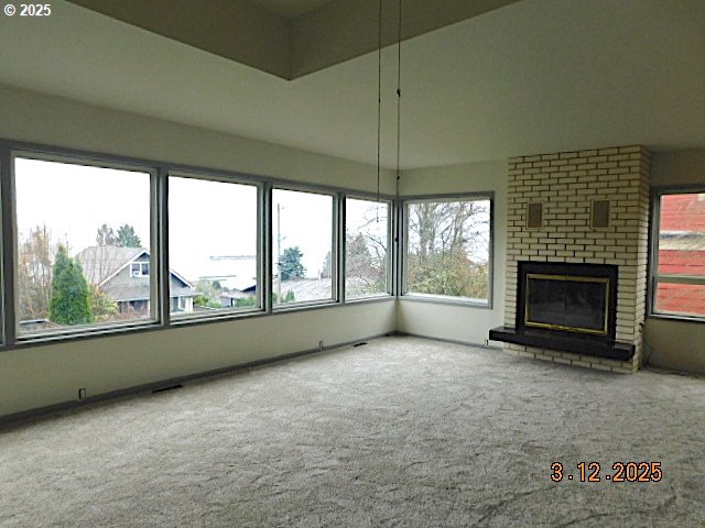 unfurnished living room with carpet flooring and a fireplace