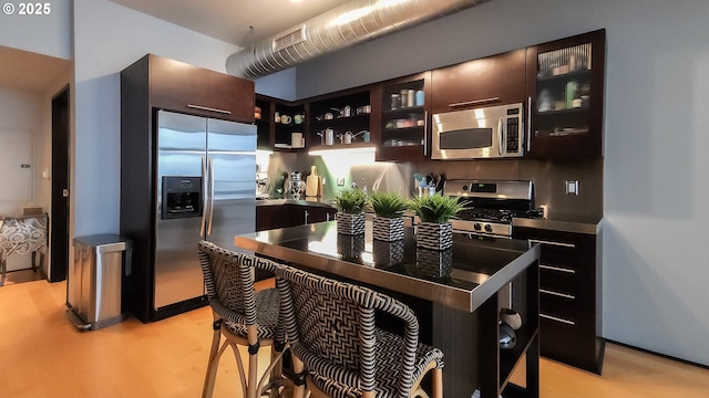 1400 NW Irving St Unit 715, Portland, OR 97209 - kitchen featuring stainless steel appliances, dark brown cabinetry, glass insert cabinets, open shelves, and light wood-style floors