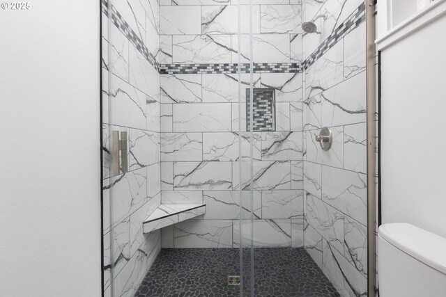 bathroom featuring toilet and a tile shower