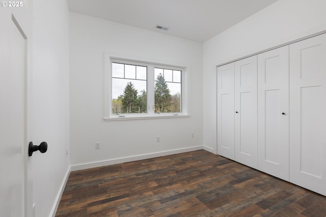 unfurnished bedroom with dark hardwood / wood-style flooring and a closet