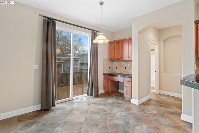 kitchen featuring decorative light fixtures, built in desk, and tasteful backsplash