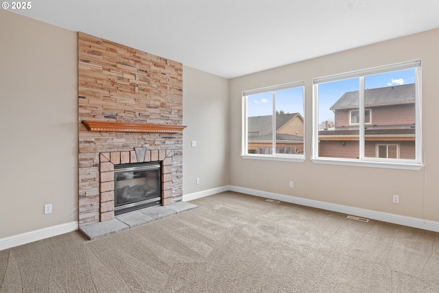 unfurnished living room featuring a stone fireplace and light carpet