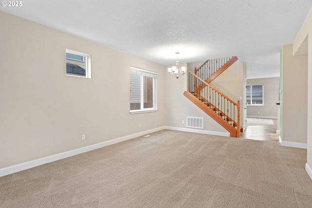 carpeted spare room featuring a notable chandelier