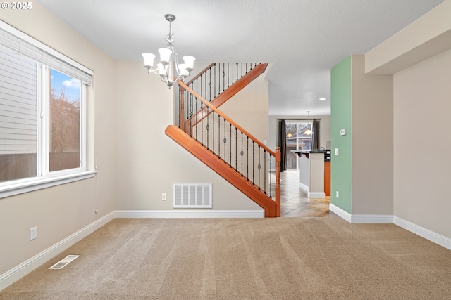 empty room with light colored carpet and a chandelier