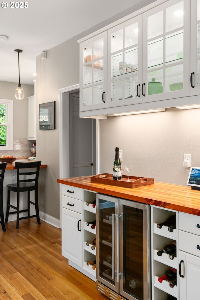 17 S Curry St, Portland, OR 97239 - indoor dry bar with beverage cooler, light wood-type flooring, hanging light fixtures, tasteful backsplash, and baseboards