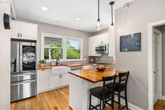 17 S Curry St, Portland, OR 97239 - kitchen featuring butcher block countertops, appliances with stainless steel finishes, a sink, white cabinets, and recessed lighting