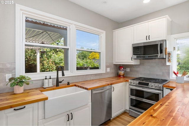 17 S Curry St, Portland, OR 97239 - kitchen featuring wood counters, stainless steel appliances, a sink, decorative backsplash, and white cabinetry