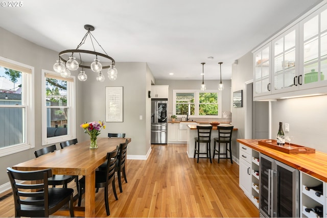 17 S Curry St, Portland, OR 97239 - dining area featuring beverage cooler, light wood-style flooring, a bar, baseboards, and recessed lighting