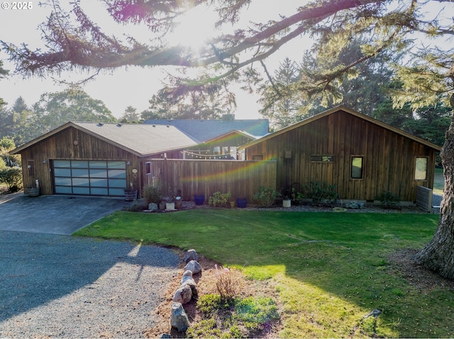 view of front facade with a garage, driveway, a front lawn, and fence