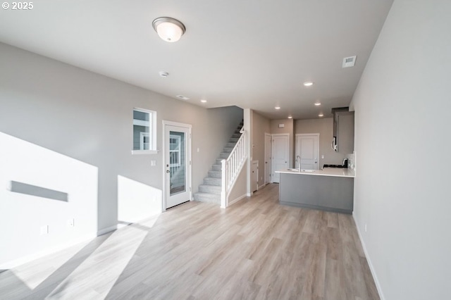 unfurnished living room featuring sink and light wood-type flooring