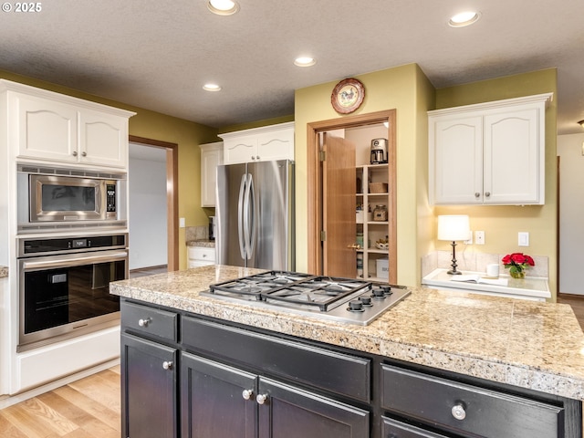 29643 SW Young Way, Wilsonville, OR 97070 - kitchen featuring stainless steel appliances, white cabinetry, recessed lighting, light wood-style floors, and tile countertops