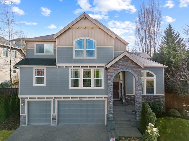 craftsman house featuring an attached garage, board and batten siding, fence, stone siding, and driveway