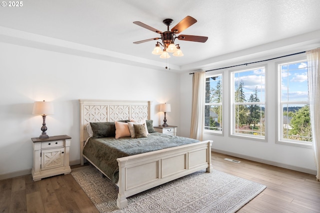 bedroom featuring light wood-type flooring, baseboards, visible vents, and a ceiling fan