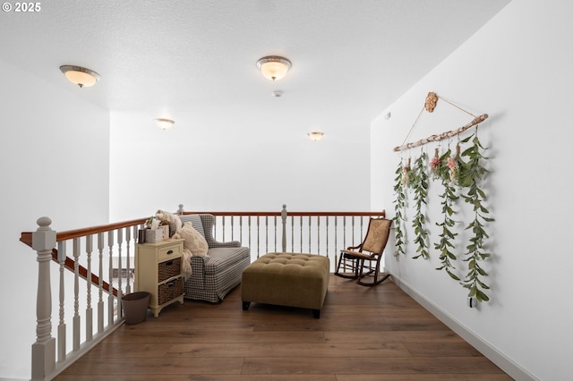 living area featuring a textured ceiling, baseboards, hardwood / wood-style floors, and an upstairs landing