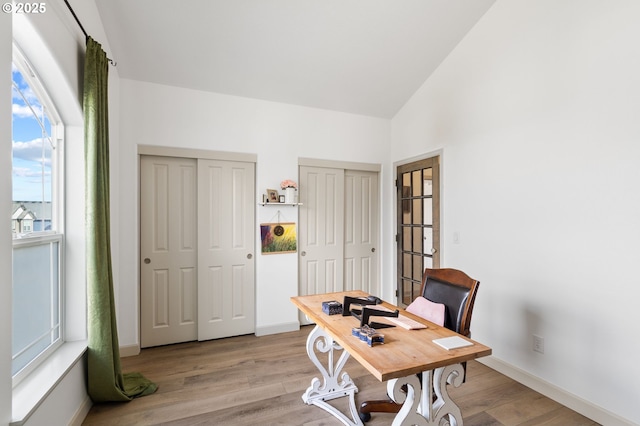 office space featuring vaulted ceiling, baseboards, and wood finished floors