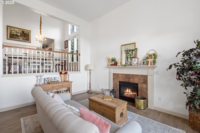 living area featuring an inviting chandelier, a fireplace, baseboards, and wood finished floors