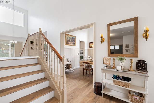 staircase featuring a notable chandelier, a high ceiling, and wood finished floors