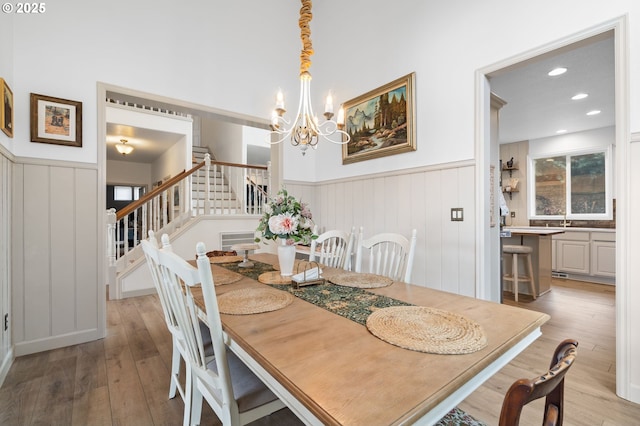 dining area featuring a wainscoted wall, stairway, and wood finished floors