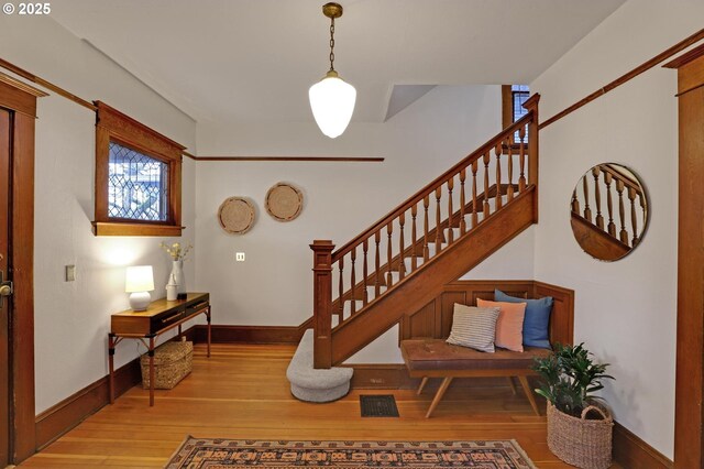 staircase with wood finished floors, visible vents, and baseboards