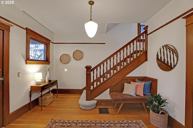 stairway featuring wood finished floors, visible vents, and baseboards