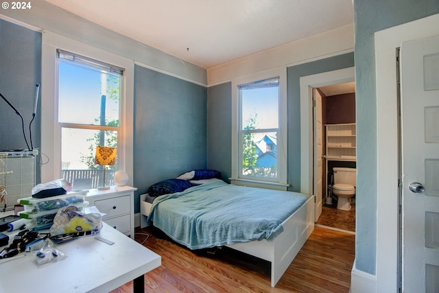 bedroom with multiple windows, wood-type flooring, and ensuite bathroom