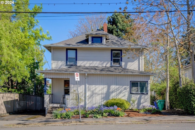 traditional style home featuring fence, roof with shingles, and a chimney
