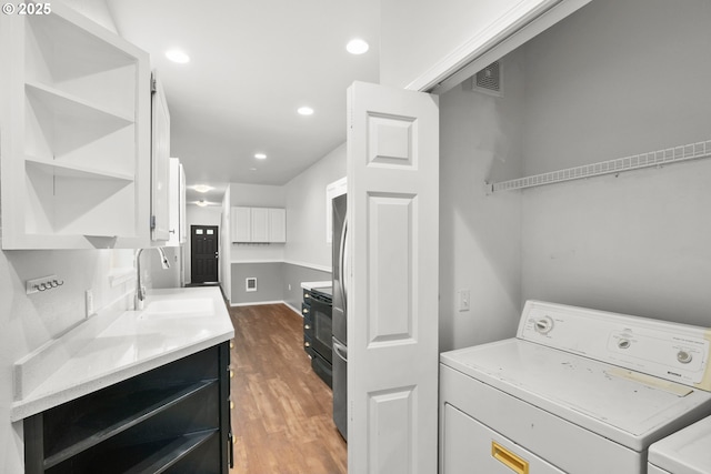 clothes washing area featuring washing machine and dryer, wood finished floors, and recessed lighting