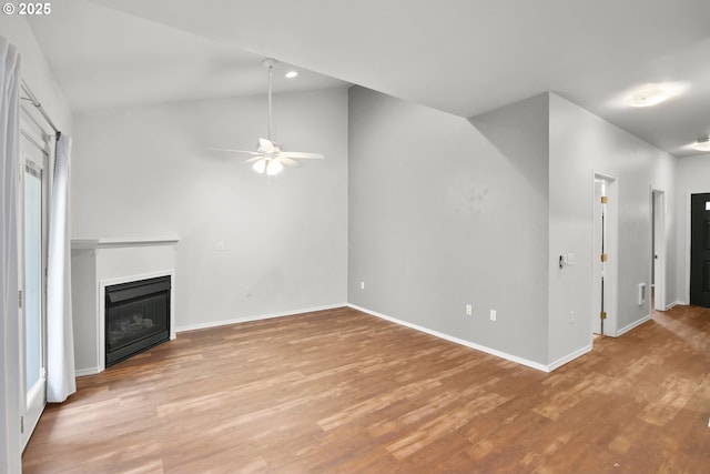 unfurnished living room featuring a ceiling fan, a fireplace, light wood-style flooring, baseboards, and vaulted ceiling