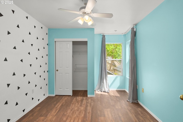 unfurnished bedroom featuring wood finished floors, a closet, baseboards, and ceiling fan